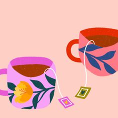 two coffee mugs with tea bags on them, one is pink and the other is blue