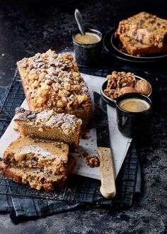 sliced loaf of bread with powdered sugar on top and two cups of coffee in the background