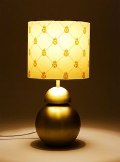 a lamp that is sitting on top of a table next to a light fixture with a yellow shade over it