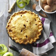 an apple pie on a wooden table next to other ingredients and utensils for baking