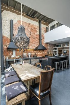 an industrial style kitchen and dining room with exposed brick wall, black pendant lights, wooden table and chairs