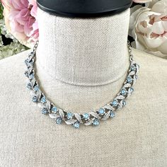 Coro Baby Blue Rhinestone and Silver Leaves Garland Necklace featuring a mid-century garland necklace by Coro, comprising icy silver textured leaves alternating with round faceted baby blue rhinestones.  This pretty necklace has smooth silver tone chain links with a hook clasp signed '©Coro' in script and the iconic openwork teardrop finial at the opposite end.  Can we worn any length up to a maximum of 43cm long and it weighs 30.9g. This beautiful piece of jewellery began its journey many years Cinderella Quinceanera Themes, Cinderella Quinceanera, Leaves Garland, Quinceanera Themes, Silver Leaves, Pretty Necklace, Leaf Garland, Pretty Necklaces, Chain Links