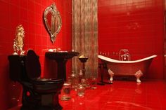 a bathroom with red walls and flooring has a claw foot tub in the corner