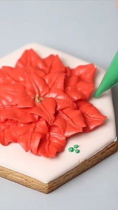 the cake is decorated with red flowers and green leaves on it's side,