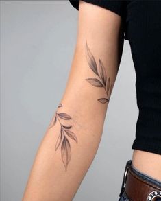 a woman's arm with a tattoo on it that has leaves growing out of it