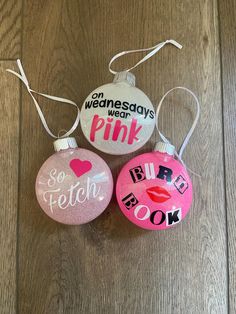 three christmas ornaments with pink designs on them