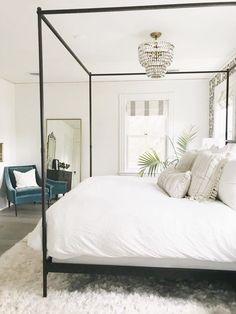 a bedroom with a four poster bed and white carpeted flooring in front of a mirror