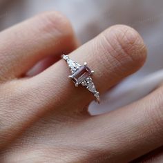 a woman's hand with a diamond ring on top of her finger and an arrow shaped stone in the middle