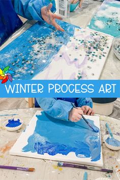 a child is painting with blue and white paint on the paper while another child holds their hand out to touch it