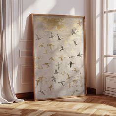 a painting on the floor in front of a window with birds flying over it and white curtains