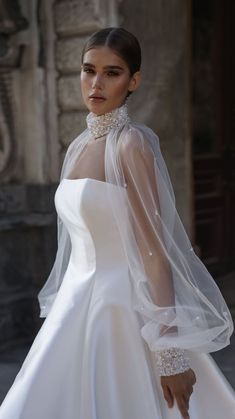 a woman in a white wedding dress with a long veil on her head and neck