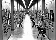 an old black and white photo of people working on electrical equipment in a room full of switches