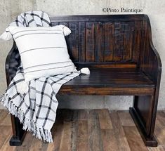 a wooden bench sitting on top of a hard wood floor next to a white and black pillow