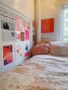 a bed sitting under a window next to a wall with posters on it