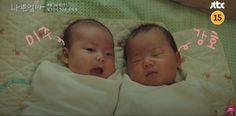 two baby babies laying next to each other on top of a white blanket with pink writing