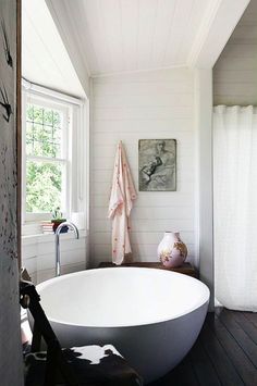 a large white bath tub sitting next to a window