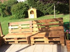 a wooden bench made out of pallets sitting on top of a tiled floor next to a tree