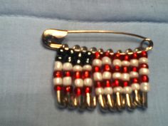 a red, white and blue beaded brooch on a light blue fabric background