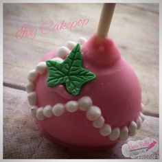 a close up of a pink cake with green leaves on it and beads around the base