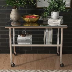 a table with books and a bowl of fruit on it next to a brick wall