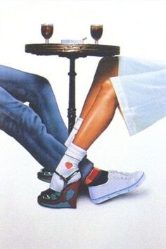 two people sitting at a table with their feet on the top of each other's legs