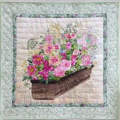 a quilted potted planter with pink and white flowers on it's side