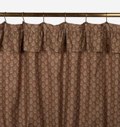 the curtain is hanging on a rod and has a brown flower pattern with white flowers