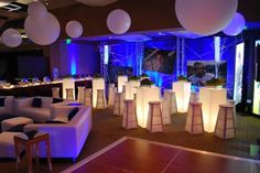 a room filled with white couches and tables covered in blue lights at night time