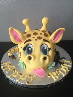 a cake with a giraffe's face on it that says happy birthday