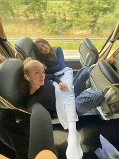 two women sitting in the back seat of a car with their feet on the floor