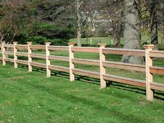 a wooden fence in the middle of a grassy field