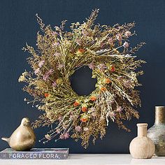 an arrangement of vases and a wreath on a table with books in front of it