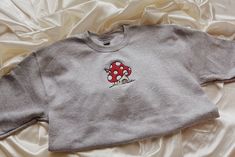 "Mushroom House Embroidered Sweatshirt! Embroidered on a cotton/polyester blend crewneck sweatshirt! This design is simple and minimalistic perfect for the cottage core look! -Embroidery design measures 5\" x 4\" -See product pictures for shirt sizing chart. -All sweatshirts are handmade on an embroidery machine so there may be slight differences, but we only sell the sweatshirts that meet our high-quality standards. -To maintain the quality of your sweatshirt and the embroidery design make sure Cotton Sweatshirt With Mushroom Print, Cotton Long Sleeve Sweatshirt With Mushroom Print, Cotton Crew Neck Sweatshirt With Mushroom Print, Cotton Crew Neck Tops With Mushroom Print, Jean Impey, Freddy Moran, Mushroom Sweatshirt, Toadstool Mushroom, Halloween Tee Shirts