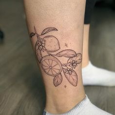 a tattoo on the leg of a woman with lemons and leaves