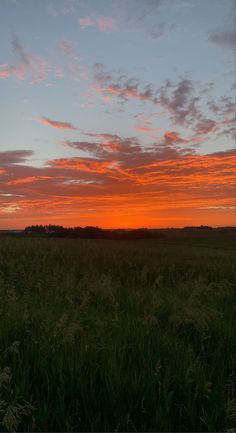 the sun is setting over an open field