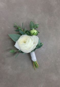 a bridal bouquet with white flowers and green leaves on the side of a concrete floor