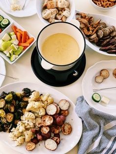 a table topped with plates of food next to bowls of vegetables and dip sauces