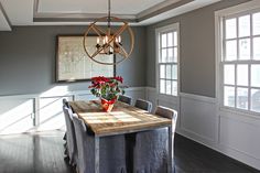 a dining room table with chairs and a chandelier hanging from it's ceiling