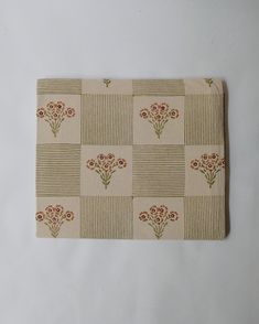 a cloth with flowers on it sitting on a white tablecloth covered in brown and tan squares