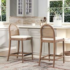 two wicker bar stools sit in front of a kitchen counter with an area rug