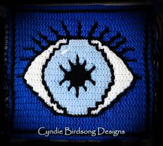 a crocheted square with an eye on the front and bottom, in blue