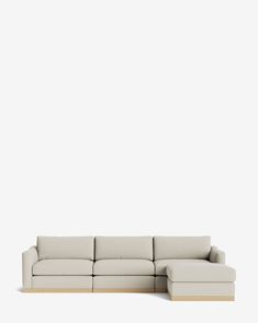 a white couch sitting on top of a wooden floor next to a wall with a light colored background