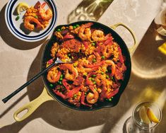 a skillet filled with shrimp, peas and rice