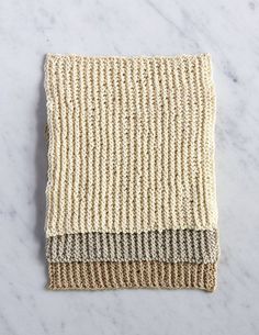 two different colors of knitted cloth on a white marble countertop, top view