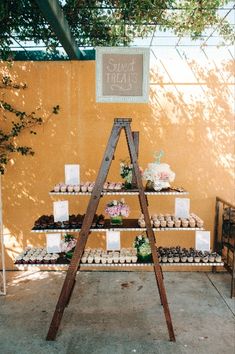 an outdoor dessert stand with cupcakes and cakes on it's display shelf