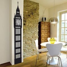 a living room with a clock on the wall next to a dining table and chairs