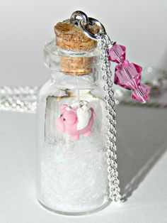 a glass bottle filled with sand and a pink pig charm on a silver plated chain