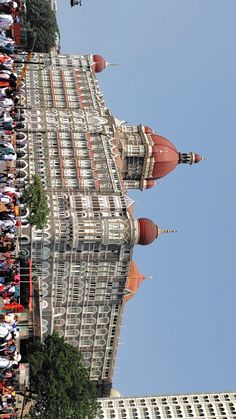 people are standing in front of a tall building with many spires on it's sides