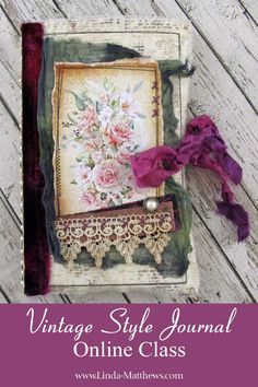 an old book with flowers and lace on it, sitting on a wooden floor next to a purple ribbon