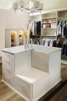 a closet with white drawers and shelves filled with clothes